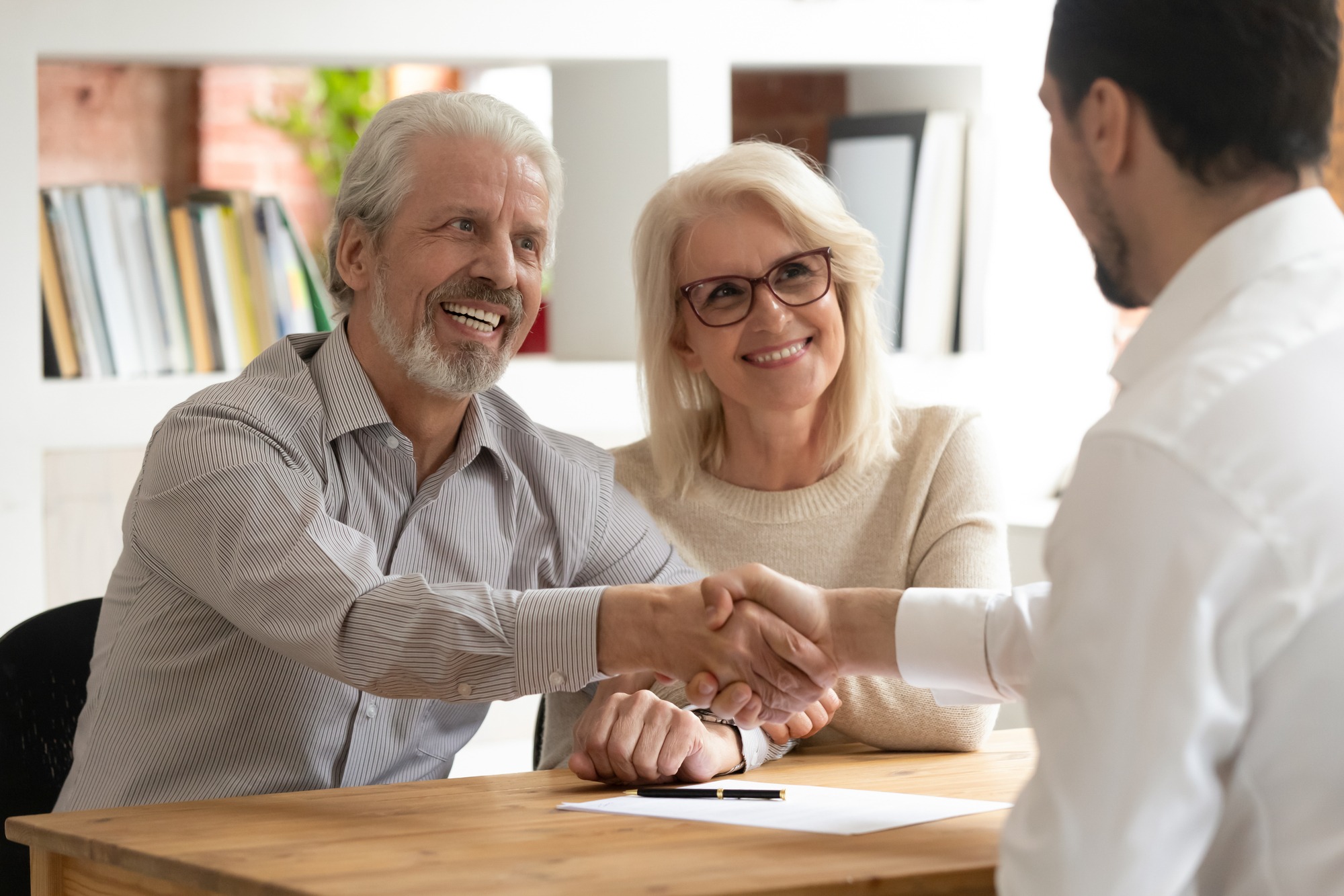Happy senior old family couple clients make insurance business deal handshake agent lawyer